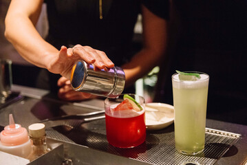 Bartender Garnishing Colorful Cocktails at Bar.