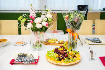 Festive table setting with fruit platter and flowers.