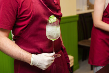 Bartender holding cocktail with cucumber garnish.