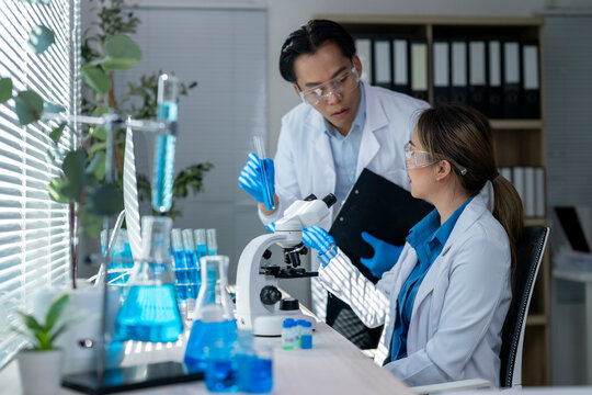 Scientists working with microscope and test tubes doing scientific research in laboratory