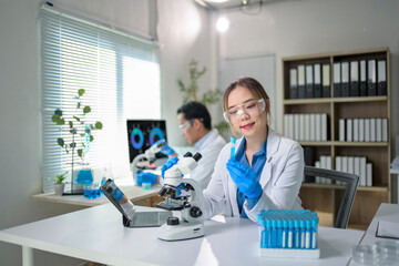 Scientists working with microscope and test tubes in laboratory