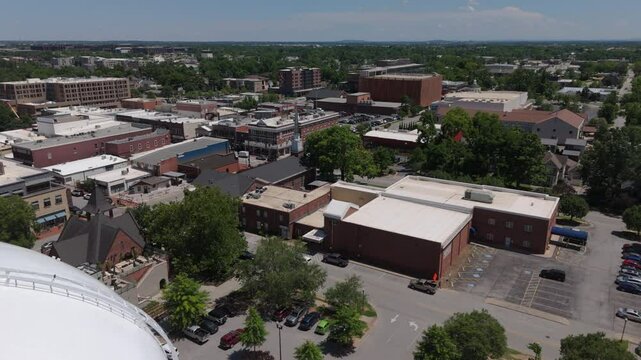 view of downtown Bentonville Arkansas flying back alongside iconic water tank