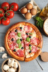 Tasty pizza and ingredients on grey wooden table, flat lay
