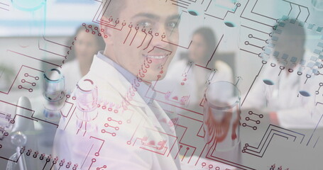 Lab coat–clad researchers analyzing clear board with circuit diagrams in lab, with glassware