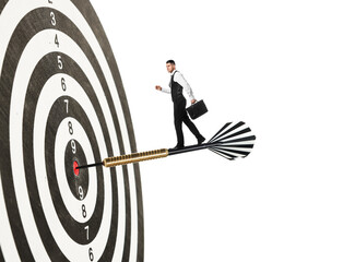 Goal achievement, business success and targeting. Businessman walking on dart sticking in center of...