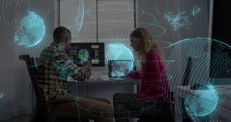 Coworkers reviewing data on desktop and laptop screens in modern office with holograms