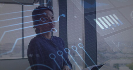Gazing adult Asian businesswoman interacting with digital overlays in office, holding documents