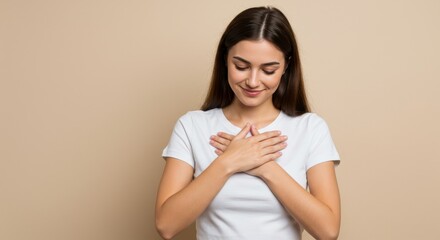 Portrait of a young woman in a white t shirt with her hands on her chest expressing gratitude