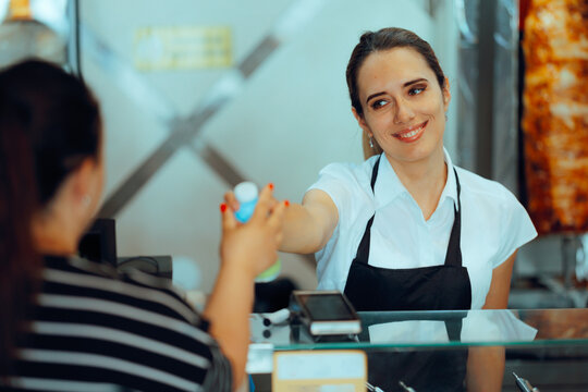 Saleswoman Serves a customer at the Counter with a Big Smile. Fast food cashier hands products to a customer - Powered by Adobe