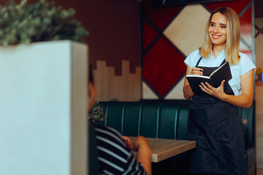 Smiling Waitress Taking order from a customer in a Restaurant. Friendly worker helps a customer decide what to eat in a diner 
