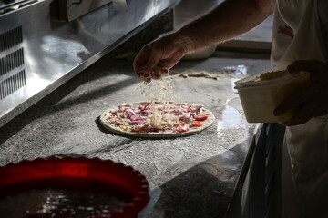 preparazione di una pizza sul bancone di una pizzeria