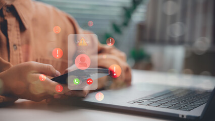 Close-up of hand holding phone with unknown caller alert and warning icons. Represents phone scam,...