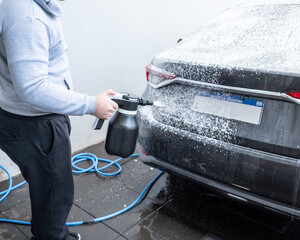 Spraying soap foam on a car with an electric foamer