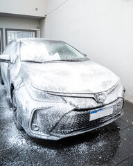 Spraying soap foam on a car with an electric foamer