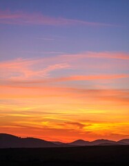Fototapeta premium Colorful gradient sky at sunset with abstract cloud formations, minimal landscape silhouette below, dreamy and atmospheric