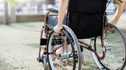 cropped shot, middle age female on wheelchair and hand grip on wheel on grass field at home she resting after being sick