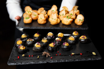Gourmet party canapés on black slate trays.