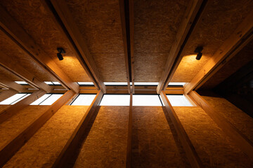Detail of skylights embedded in a triangular wooden roof of a glamping cabin. Natural light streams through, enhancing the eco-friendly and geometric forest-inspired structure.