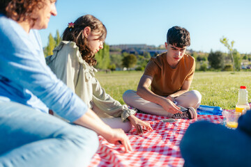 Family enjoying a sunny day playing cards at a picnic in a park