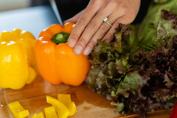 female nutritionist and chef slicing into orange bell pepper on wooden cutting board