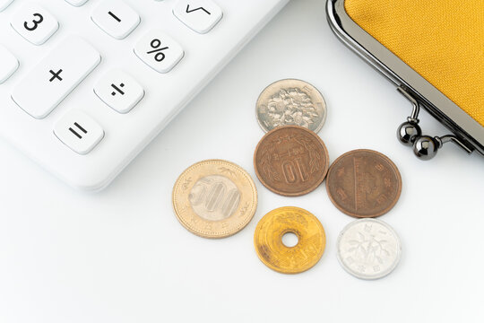 白背景に電卓と黄色のがま口財布と硬貨（日本）
