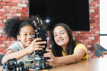 Diverse Kids Building a Robot Arm in a Science Workshop, Young Girls Engaged in Robotics and STEM Learning, Two Girls Exploring Technology and Innovation, Future Engineers