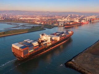Aerial view of a container ship sailing into the Port of Oakland, California, USA. The ship is...