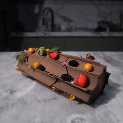uncut chocolate roll cake topped with long chocolate chips and small fruits