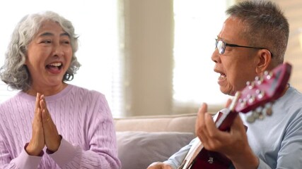 Elderly couple enjoying guitar music together on a cozy sofa in natural light living room - Powered by Adobe