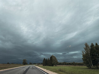 A Dramatic Sky Above an Open Road Surrounded by Expansive Lush Green Fields and Nature