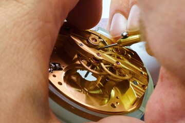 Skilled craftsman meticulously repairs watch mechanics in a well-lit workshop full of precision...