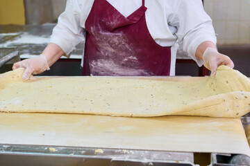 Cracker dough being prepared by a baker in a commercial kitchen during the early morning hours