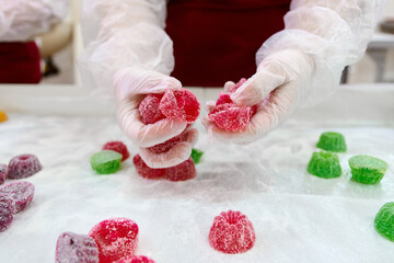 Hands holding colorful marmalade confections in a candy shop during a crafting session