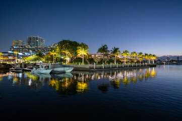 Fototapeta premium Bars and restaurants of Coconut Grove in Miami, Florida reflected in calm water of Biscayne Bay in deep morning twilight.