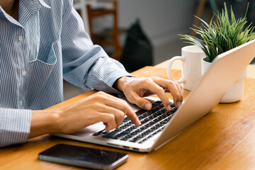 Person, hands and typing on laptop in office for email, spreadsheet and proposal or application for work. Man, online and technology with bokeh for task or drafting, writing notes and report.
