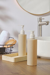 Natural pump bottles and wooden tray beside sink with mirror and clean towels. Simple and elegant...