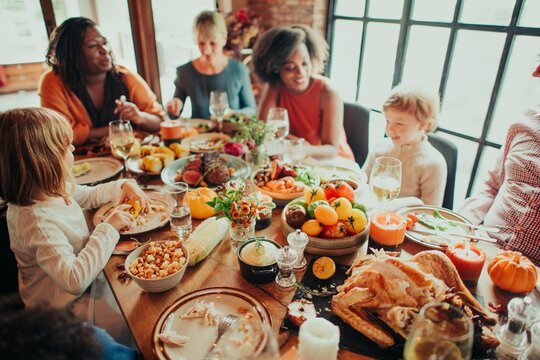 Diverse group enjoying a festive meal. Family and friends gather around a table with food, laughter, and joy. Celebrating together with a bountiful feast. Celebrations and family gathering.