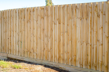 A freshly constructed timber boundary fence in a suburban residential backyard, made from vertical...