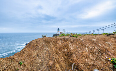 Dramatic coastal view of Point Bonita Lighthouse on a rocky cliff with a suspension bridge and powerful ocean waves, Marin Headlands, California