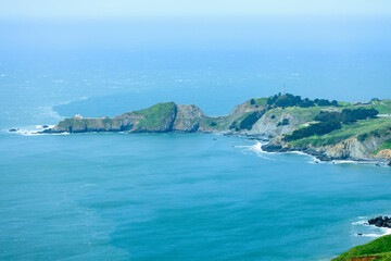 Fototapeta premium Scenic panoramic view of Marin Headlands with winding road, lush green hills, and Pacific Ocean coastline on a clear spring day, California nature landscape