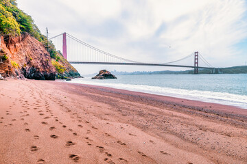 Kirby Cove Beach in California with red sand, blue ocean waves, and dramatic cliffs covered in pine trees. A hidden gem near San Francisco, perfect for nature, travel, and coastal exploration themes