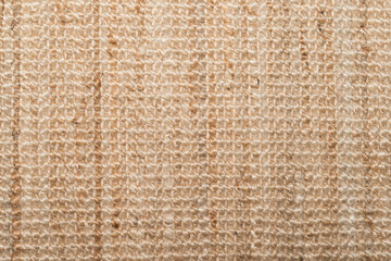 Overhead shot of a woven beige rug with visible fibers and subtle lines. Natural warm tones, ideal...