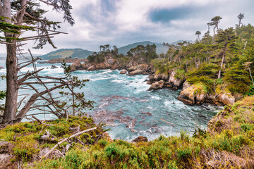 Breathtaking coastal scenery from Point Lobos, California, featuring rugged cliffs, turquoise waves, Monterey cypress trees, and dramatic skies. A pristine and wild Pacific landscape for nature lovers