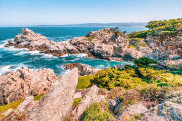 Point Lobos State Natural Reserve in California USA features turquoise waters, rugged cliffs, and vibrant coastal vegetation under a clear sky.