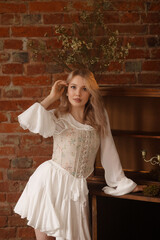 Young Caucasian woman, 20s, in white romantic dress, standing barefoot, hand on face, near old wooden cabinet, front view, red brick wall, moss floor. Concepts: dream, rustic, mystery, contrast.