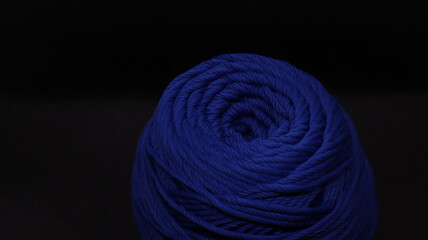 A ball of yarn in an orange color on a black background
