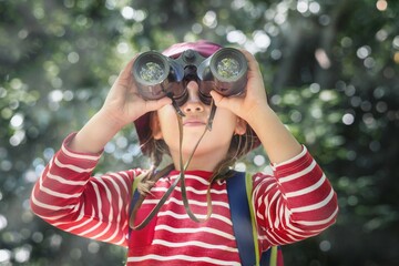 Little girl using binoculars in the forest