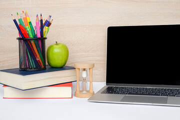 A dedicated study space featuring a laptop, books, and a fresh apple for inspiration