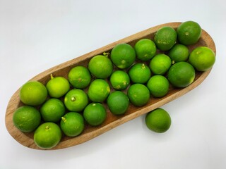 Limes in a wooden tray with white background, besides being squeezed into a drink, can also be used...