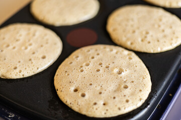 Close-up of raw pancake batter bubbling on pan during cooking, top view of homemade breakfast prep